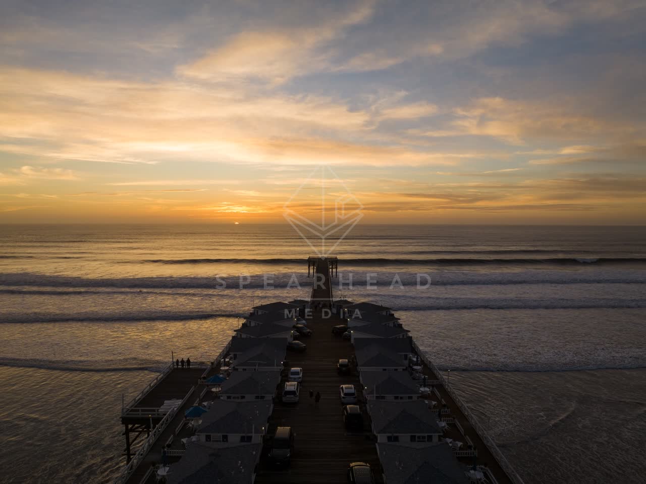 Low aerial view of the beach, the surf and the pier in Pacific Beach, with people walking.