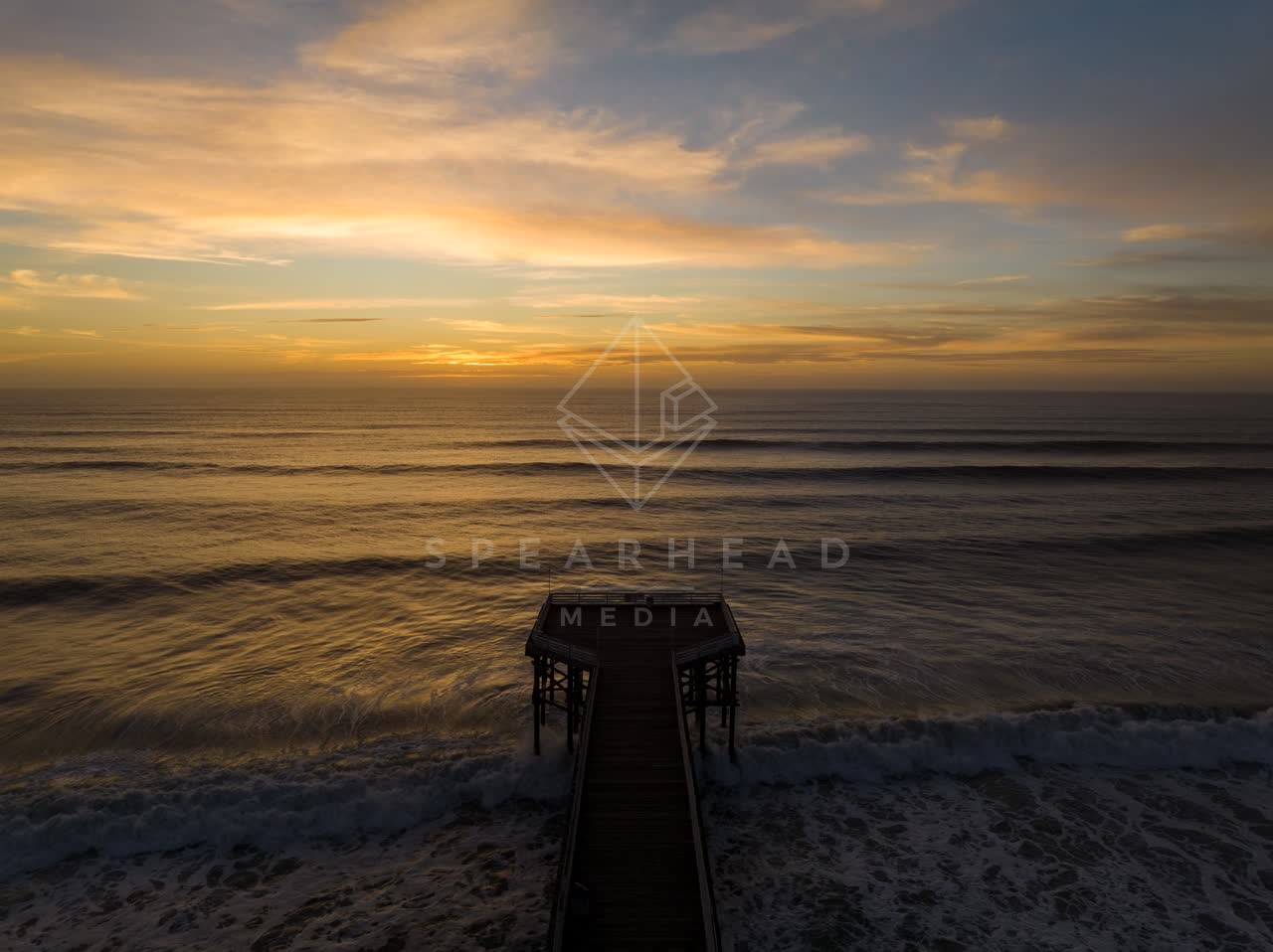 Low aerial view of the beach, the surf and the pier in Pacific Beach.