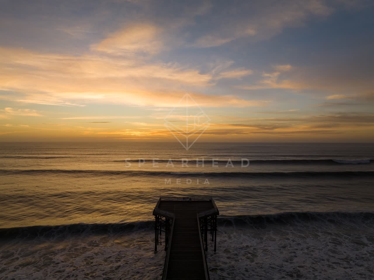Low aerial view of the beach, the surf and the pier in Pacific Beach.