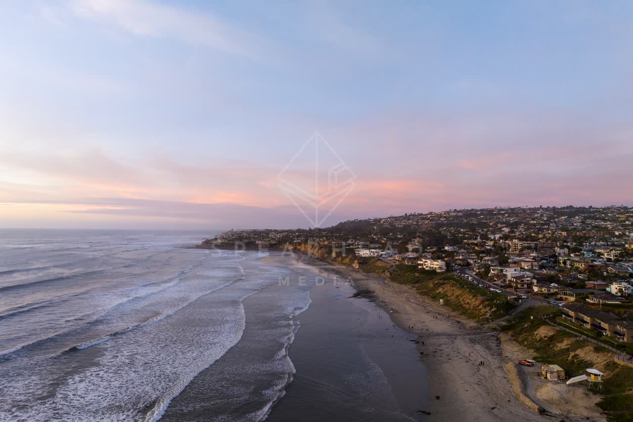 Aerial view of the beach, the surf and the ocean in Pacific Beach, with people walking.