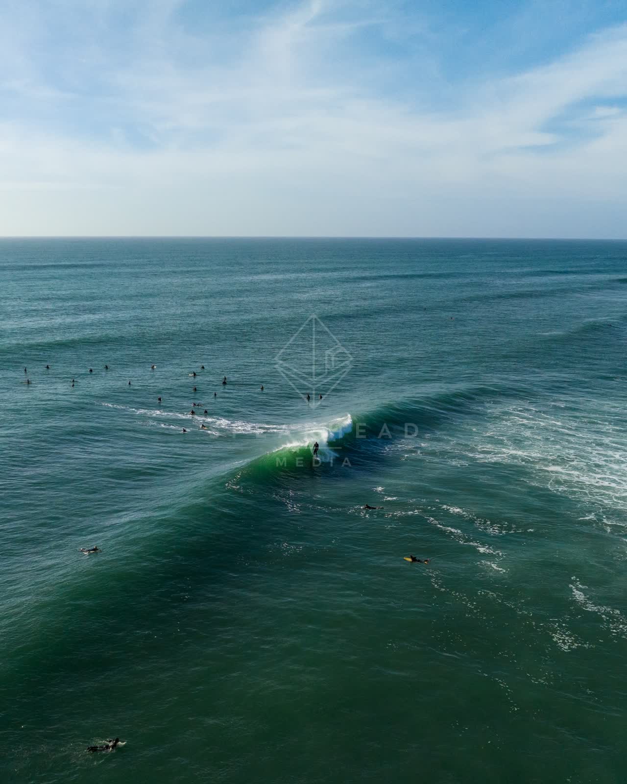 Aerial view of the beach, the surf and the ocean at Swamis, with surfers out.