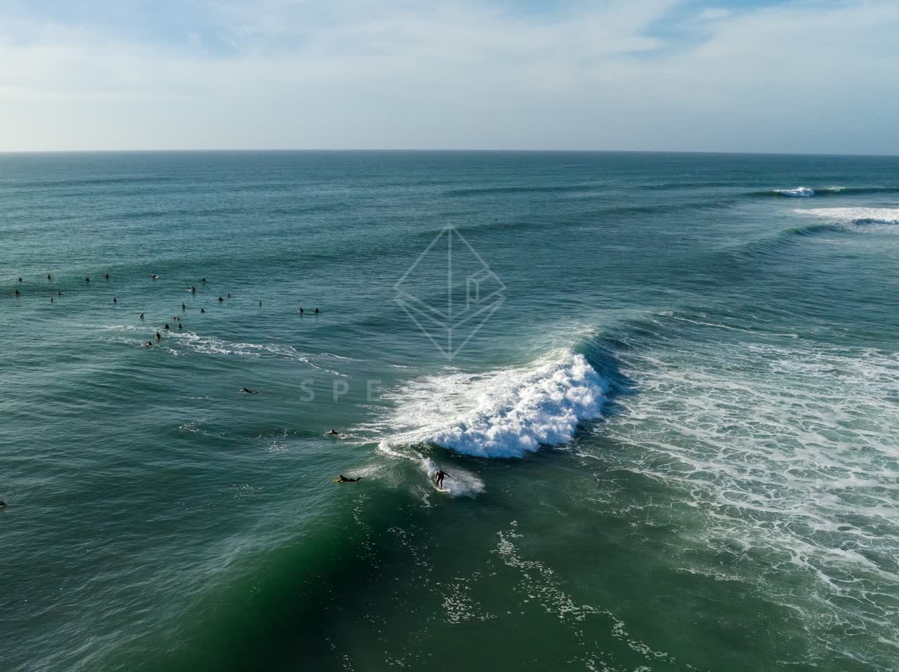 Low aerial view of the beach, the surf and the ocean at Swamis, with surfers out.