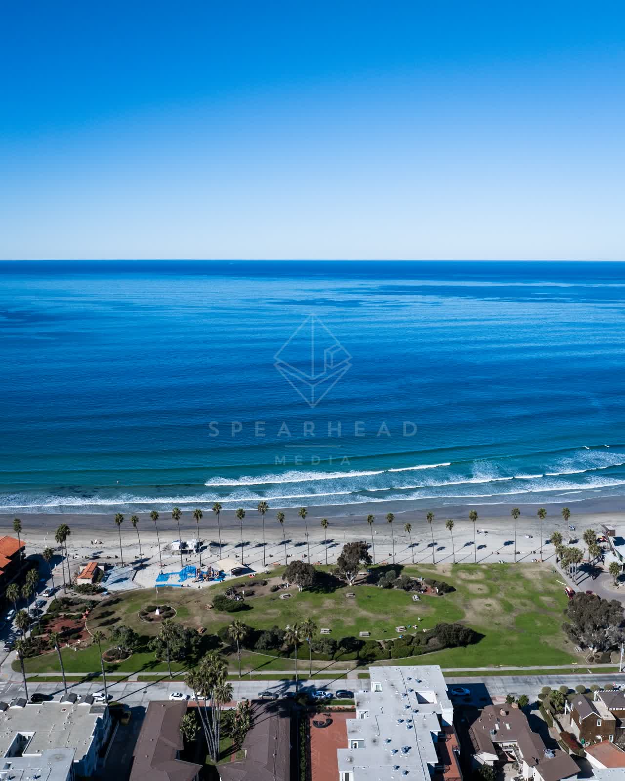 Aerial view of the beach, the surf and palm trees at La Jolla Shores, with people walking.