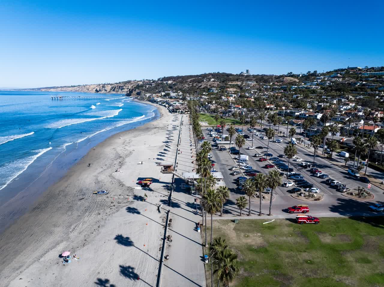 Aerial view of the beach, the surf and the pier at La Jolla Shores, with people walking.
