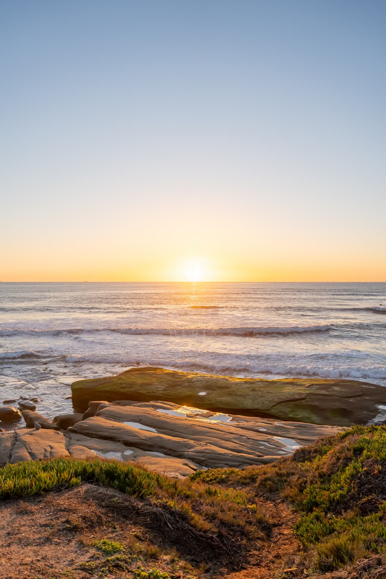 Elevated view of the cliffs, the surf and the ocean at Windansea.