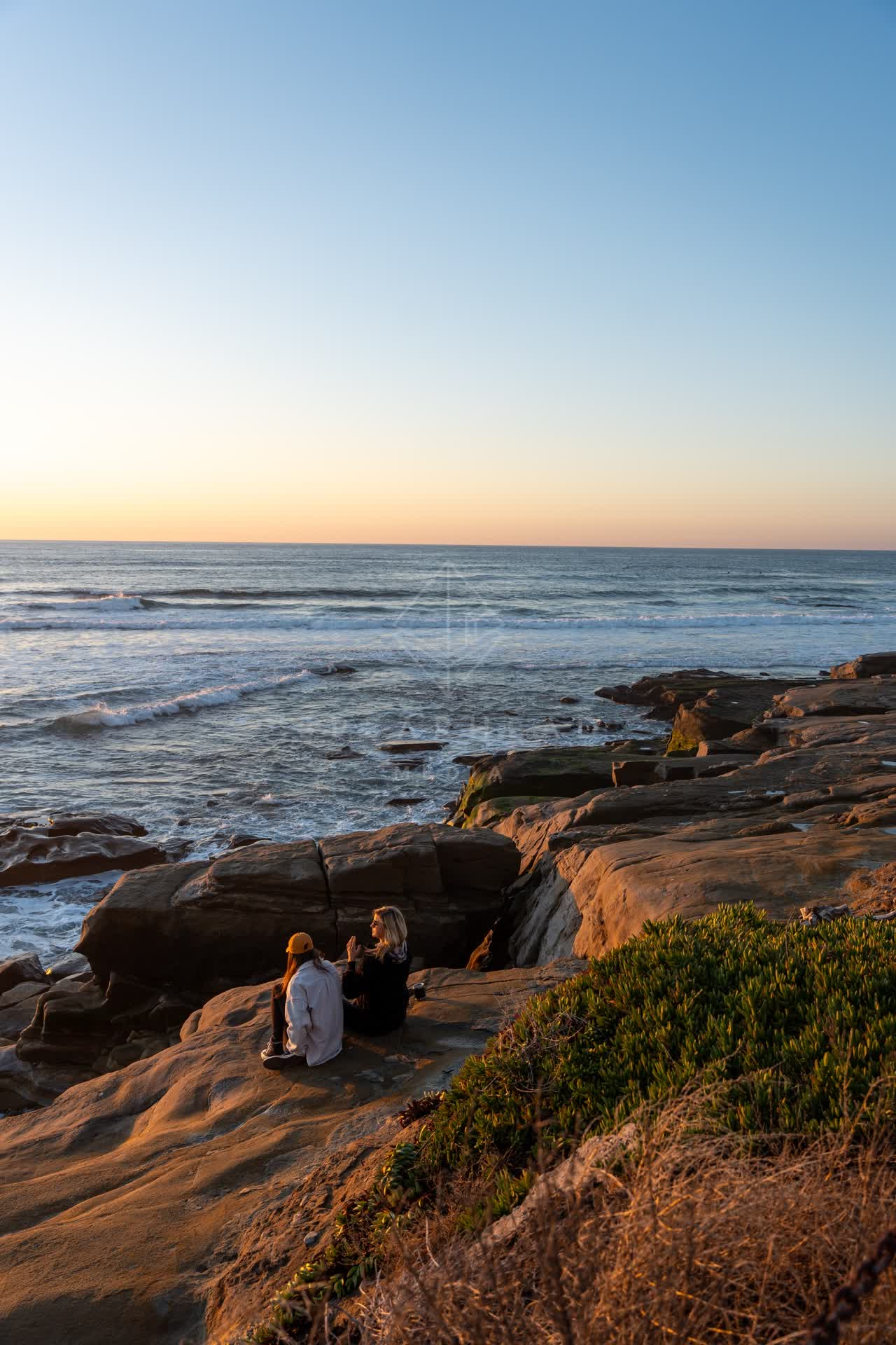 Elevated view of the cliffs, the surf and the ocean at Windansea, with a crowd gathered.