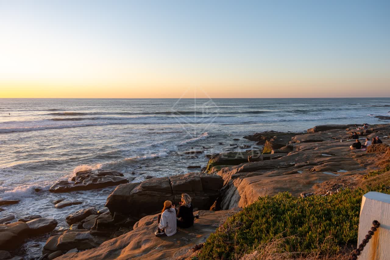 Elevated view of the cliffs, the surf and the ocean at Windansea, with a crowd gathered.