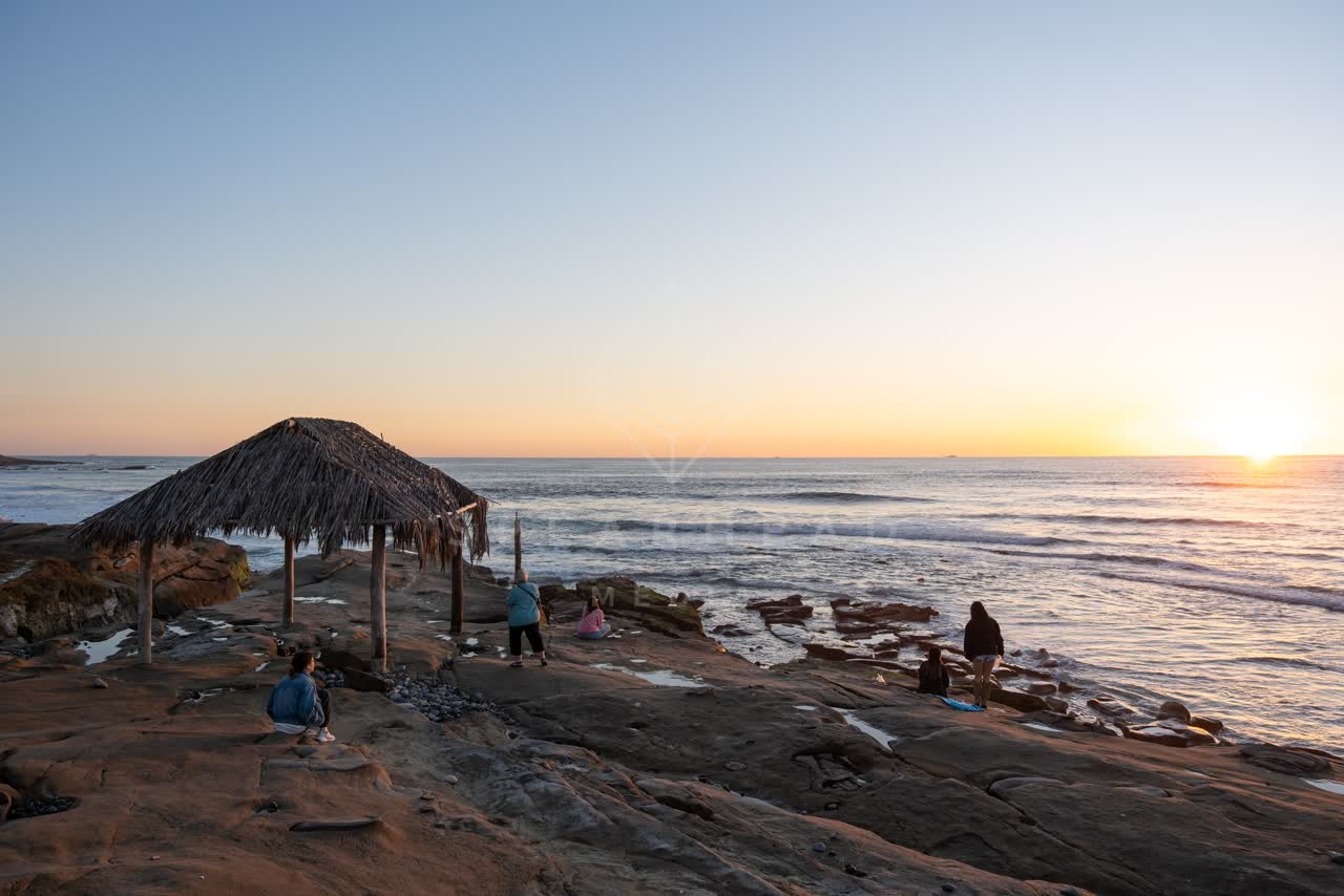 Elevated view of the cliffs, the surf and the ocean at Windansea, with a crowd gathered.