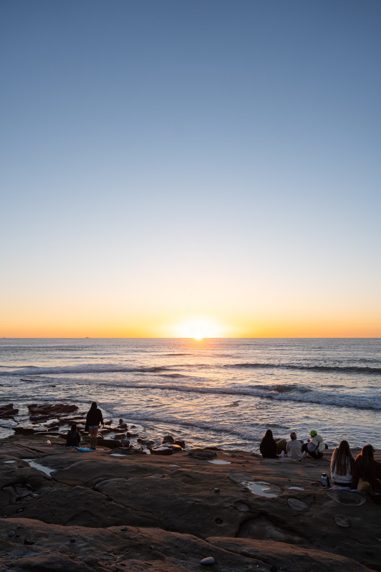 Elevated view of the cliffs, the surf and the ocean at Windansea, with a crowd gathered.
