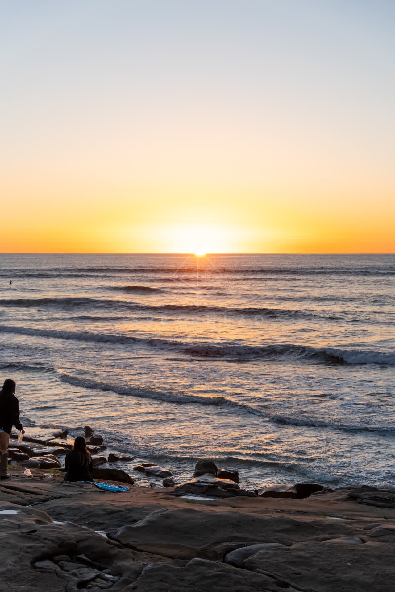 The beach, the surf and the ocean at Windansea, with people walking.
