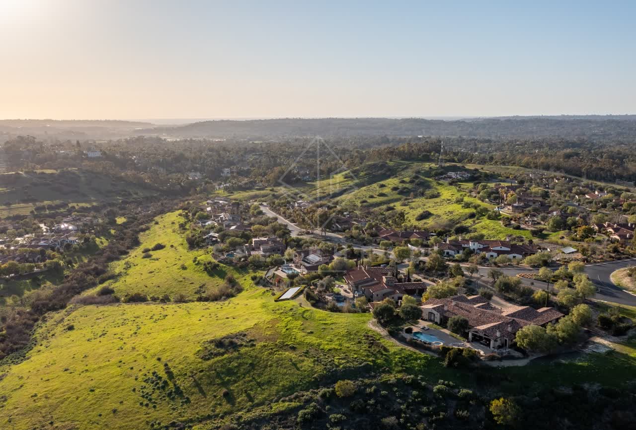 Aerial view of a residential street, homes and open country in Black Mountain Ranch.