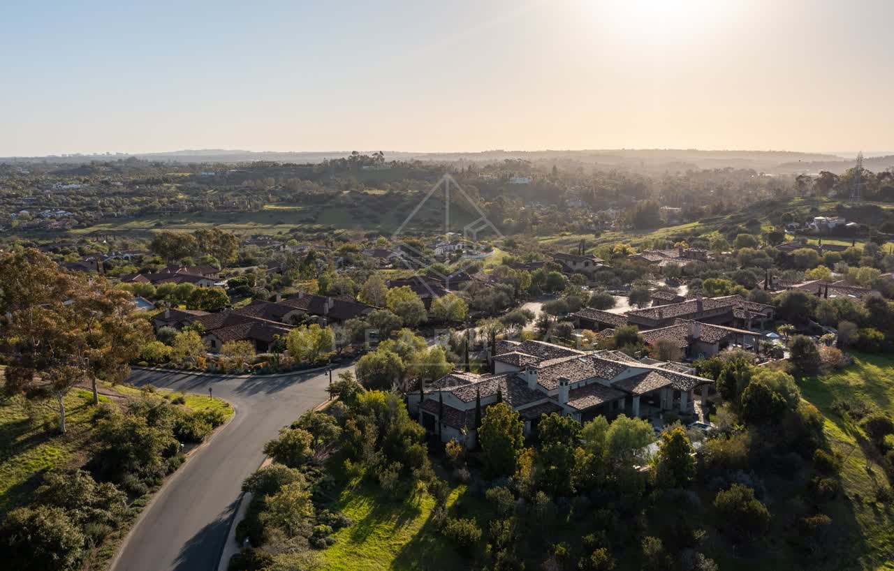 Aerial view of a residential street, homes and open country in Black Mountain Ranch.