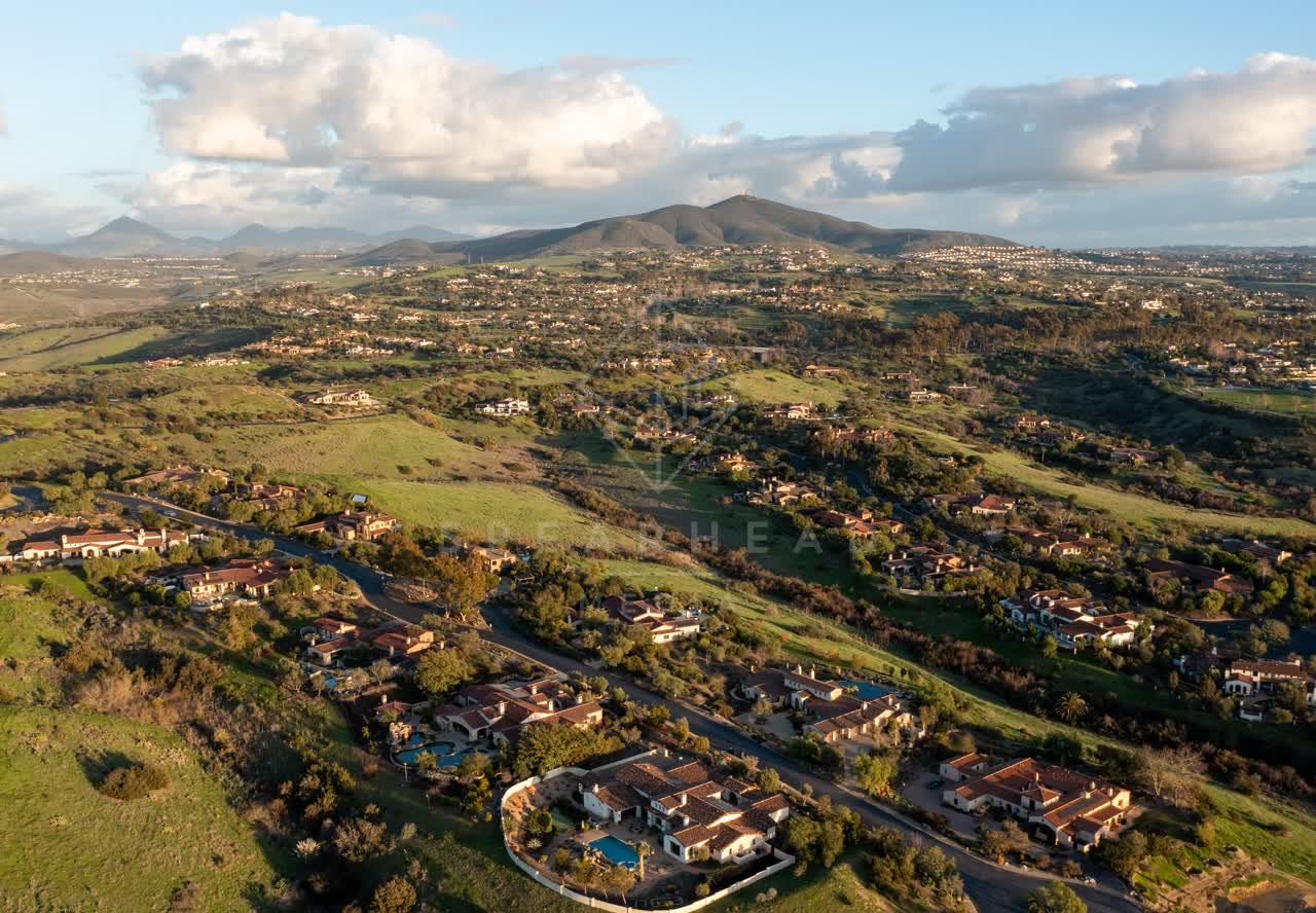 Aerial view of a residential street, homes and open country in Black Mountain Ranch.
