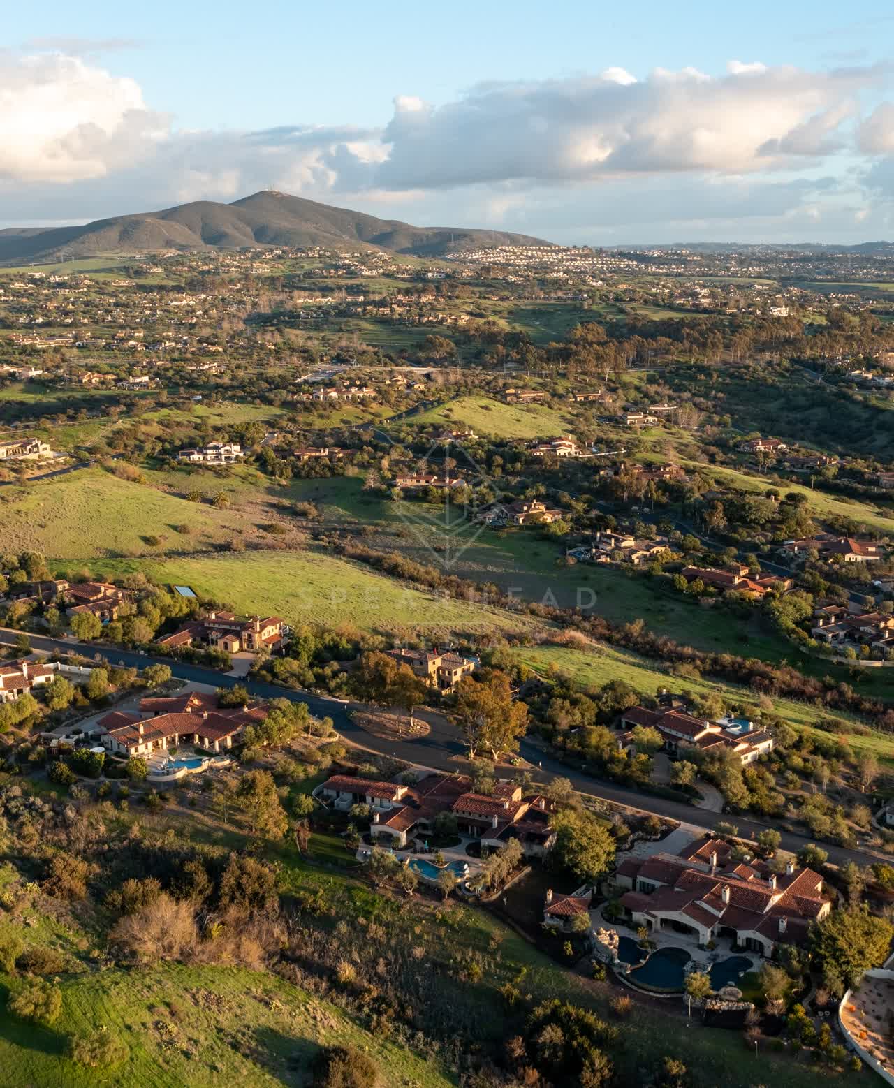 Aerial view of a residential street, homes and open country in Black Mountain Ranch.