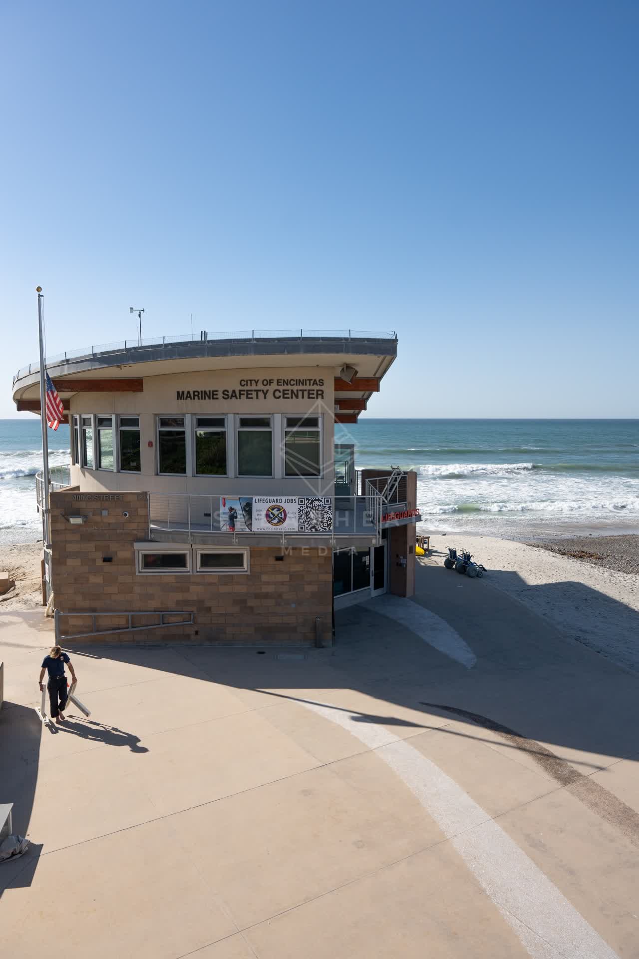 Elevated view of the beach, the surf and the ocean at Moonlight Beach, with people walking.