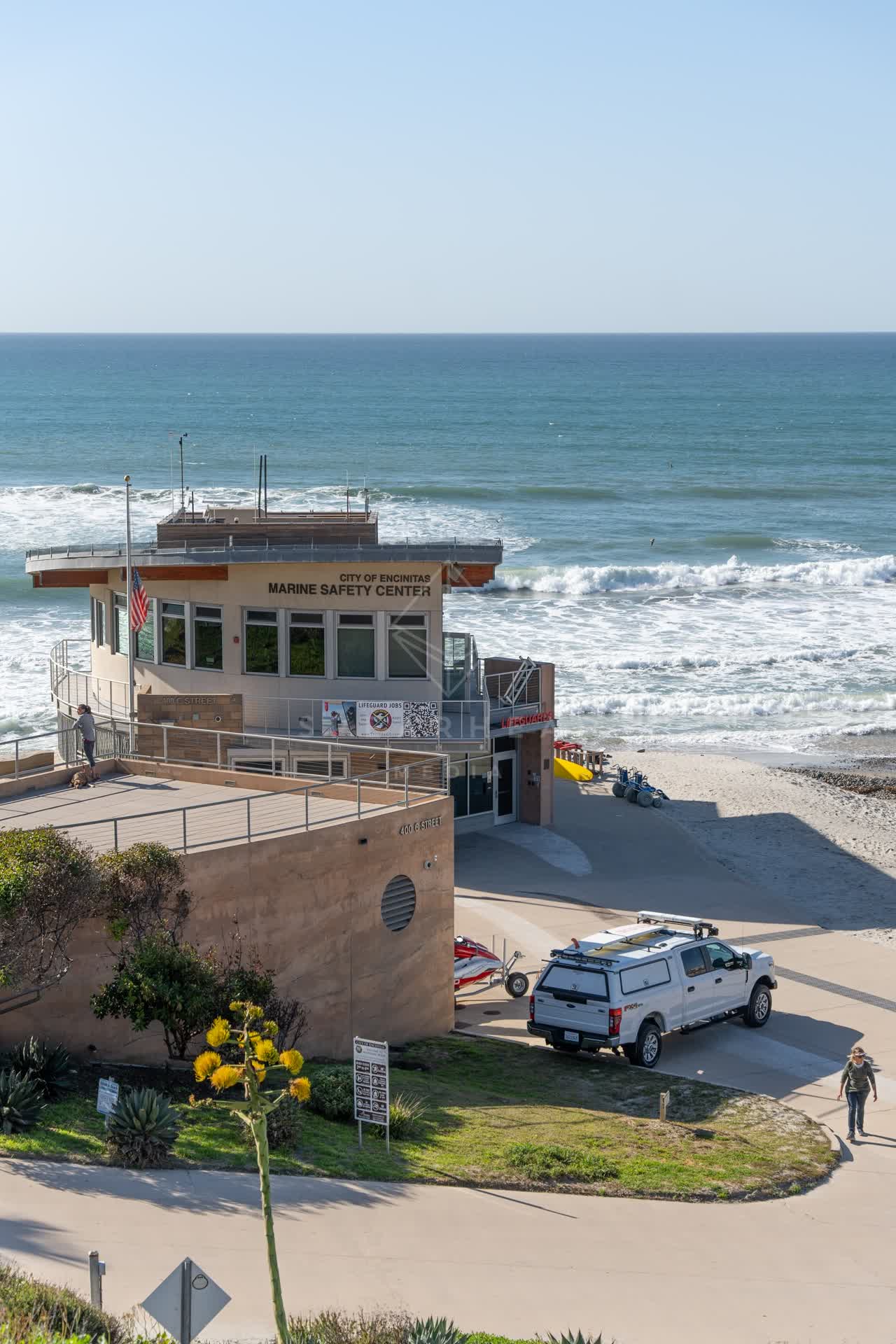 Elevated view of the beach, the surf and the ocean at Moonlight Beach, with people walking.