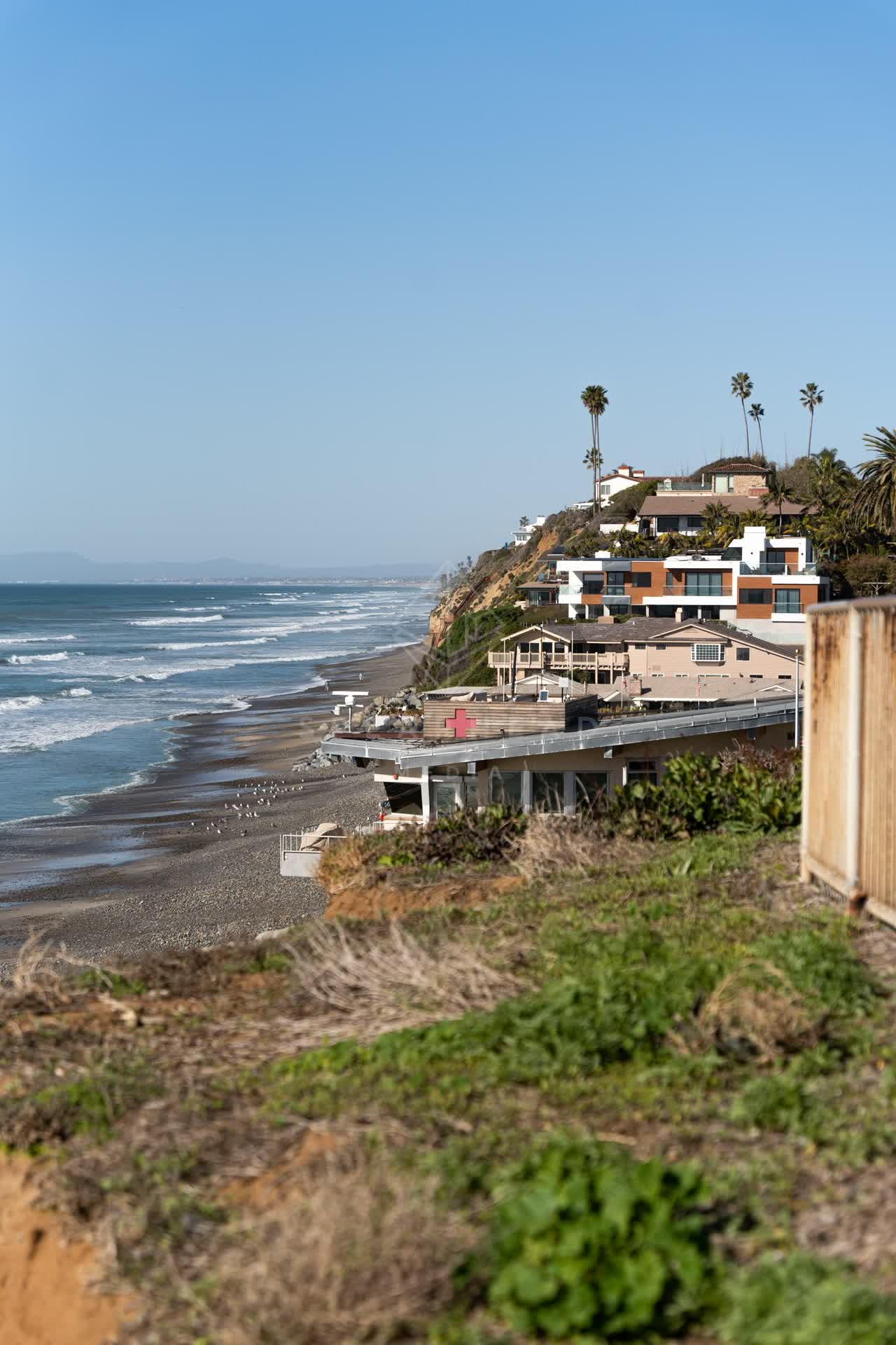 Elevated view of the cliffs, the surf and palm trees at Moonlight Beach.