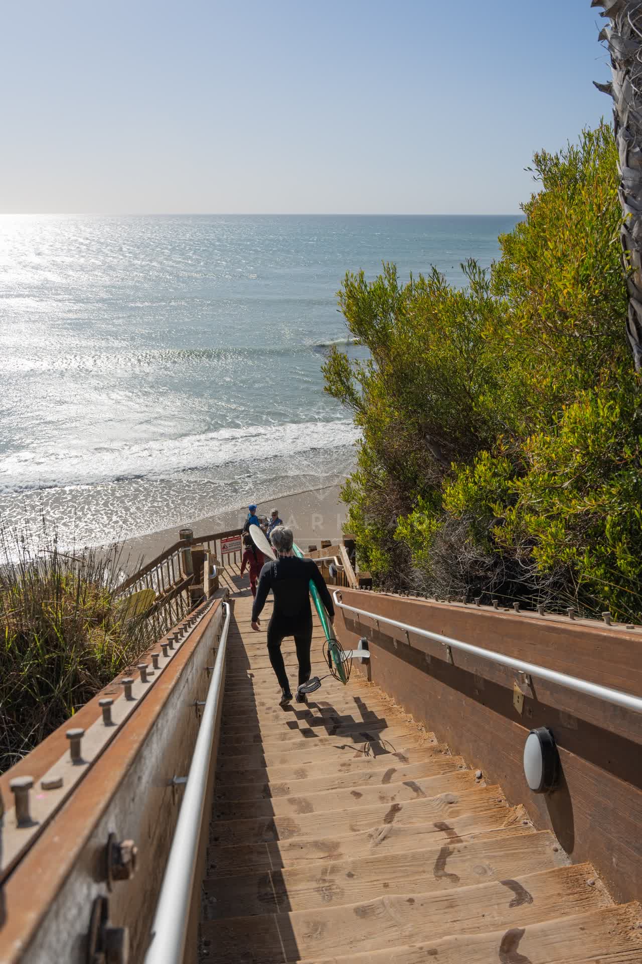 Elevated view of the cliffs, the surf and the ocean at Swamis, with surfers out.