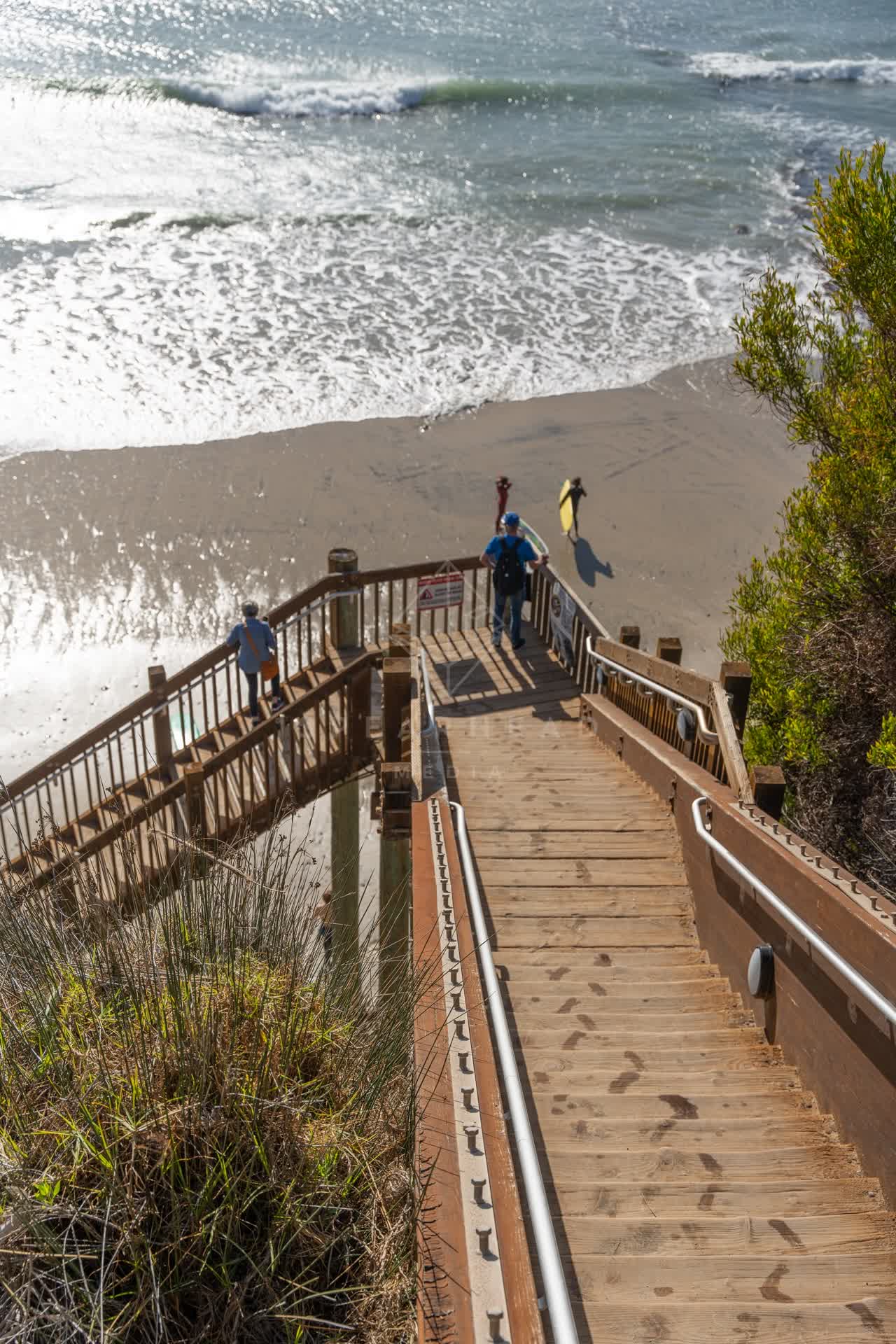 Elevated view of the cliffs, the surf and the ocean at Swamis, with people walking.