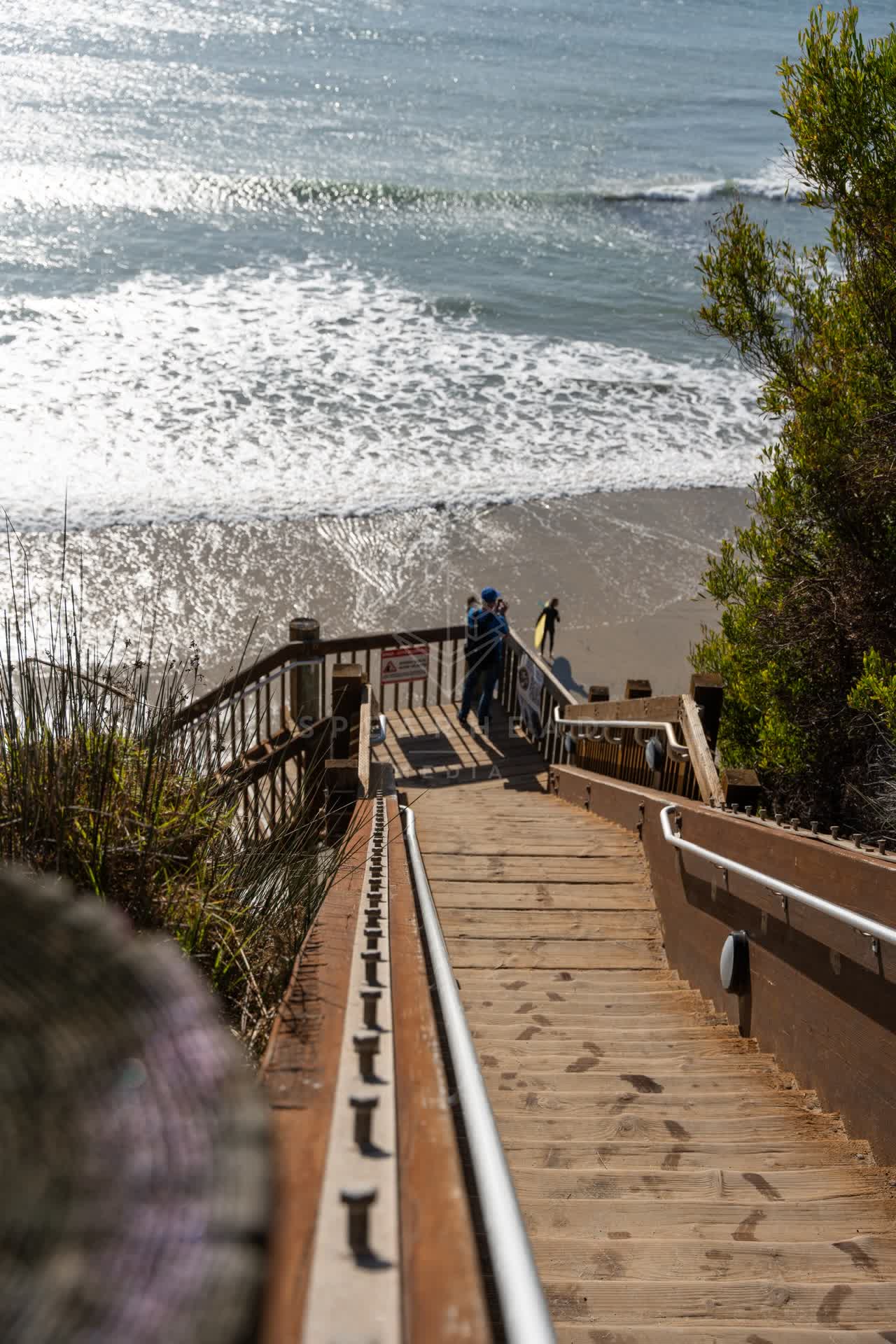 Elevated view of the cliffs, the surf and the ocean at Swamis, with people walking.