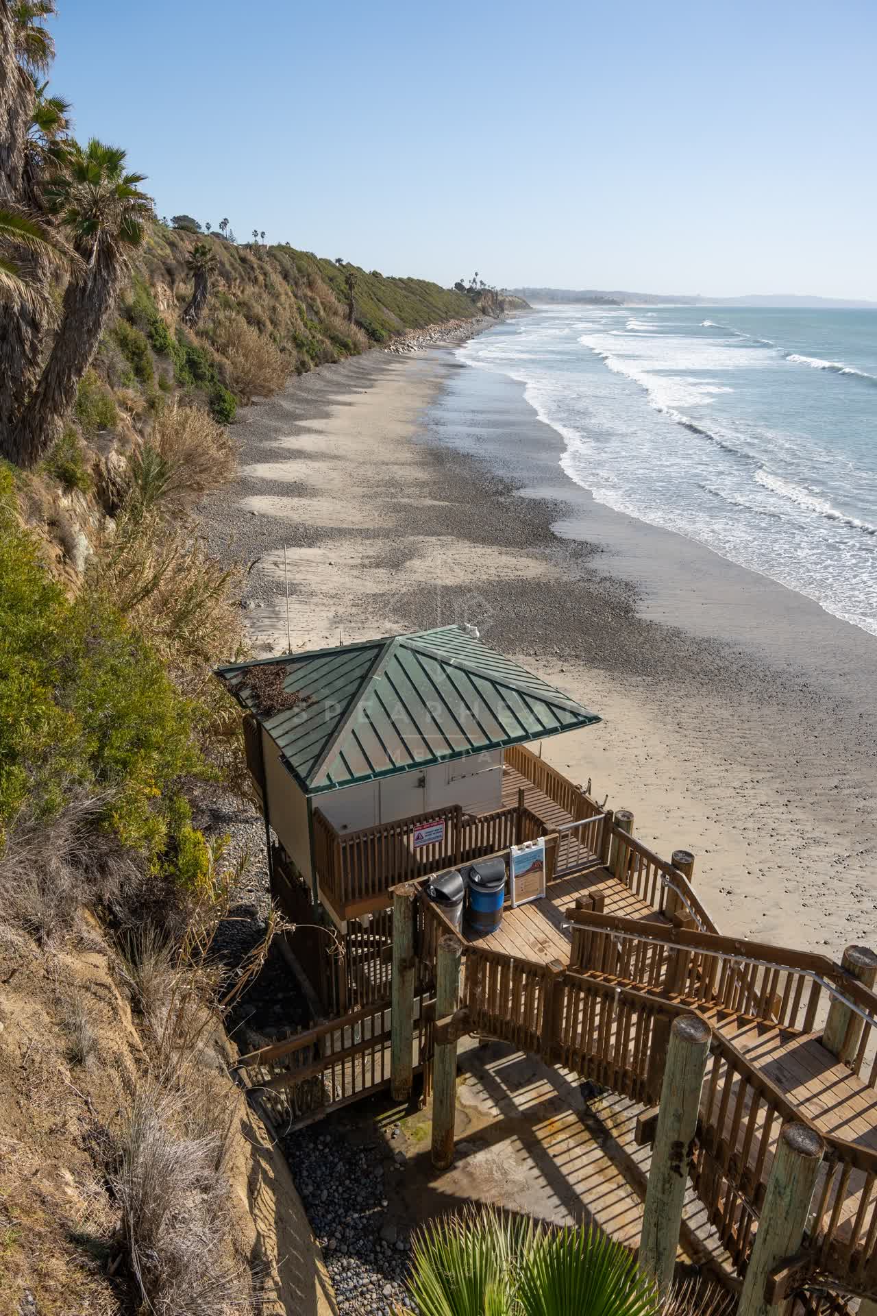 Elevated view of the cliffs, the surf and palm trees at Swamis.