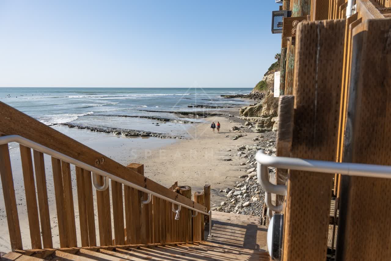 Elevated view of the beach, the surf and the ocean at Swamis, with people walking.