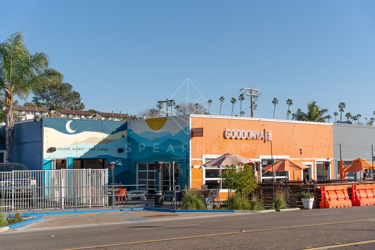 The downtown streets, palm trees and the buildings at Downtown Encinitas, with people eating outside.