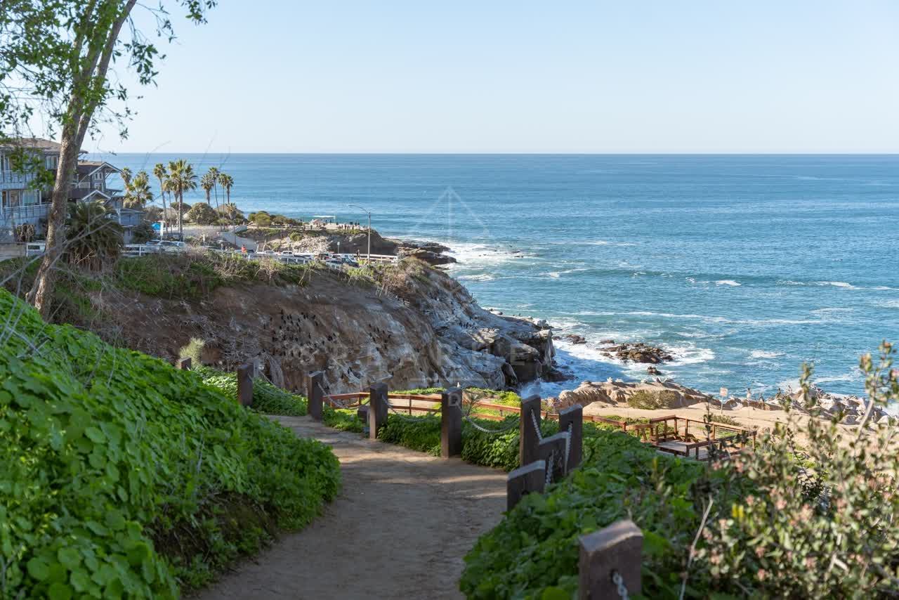 Elevated view of the cliffs, palm trees and the ocean at Coast Walk Trail, with people walking.