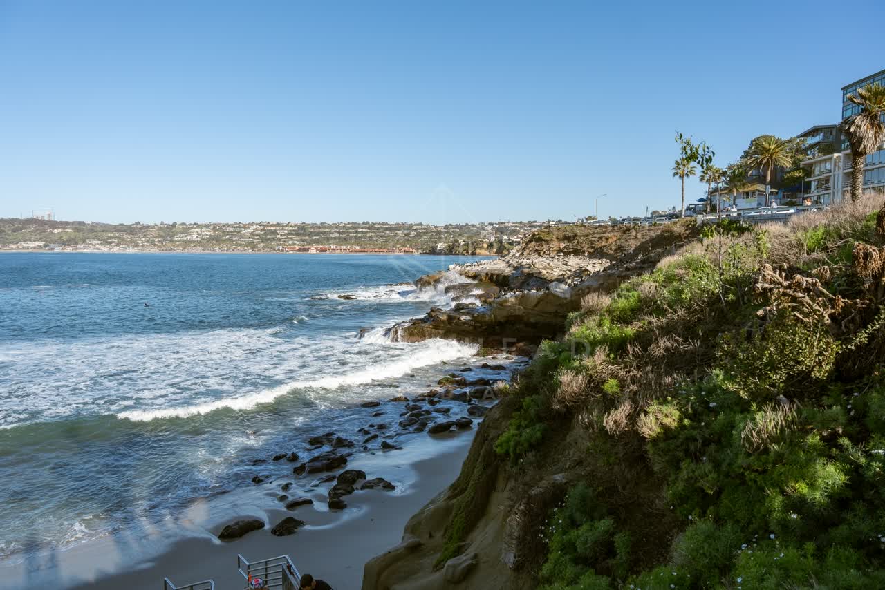 Elevated view of the cliffs, the surf and palm trees at La Jolla Cove.