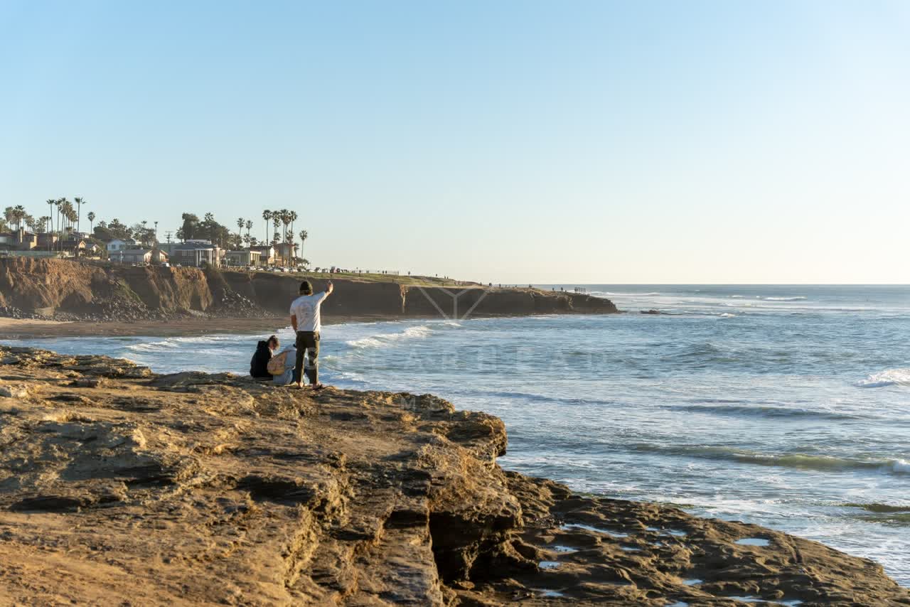 Elevated view of the cliffs, palm trees and the ocean at Sunset Cliffs, with people walking.