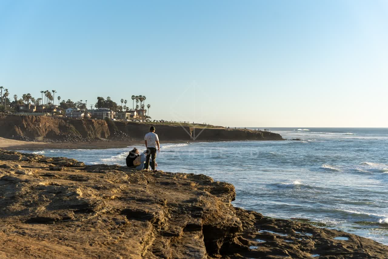 Elevated view of the cliffs, palm trees and the ocean at Sunset Cliffs, with people walking.