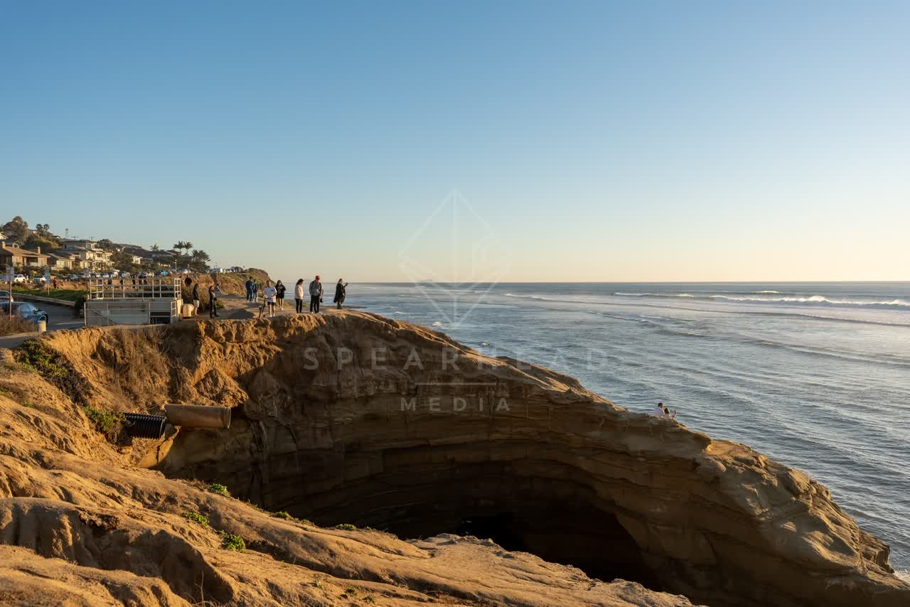 Elevated view of the cliffs, the surf and the ocean at Sunset Cliffs, with people walking.