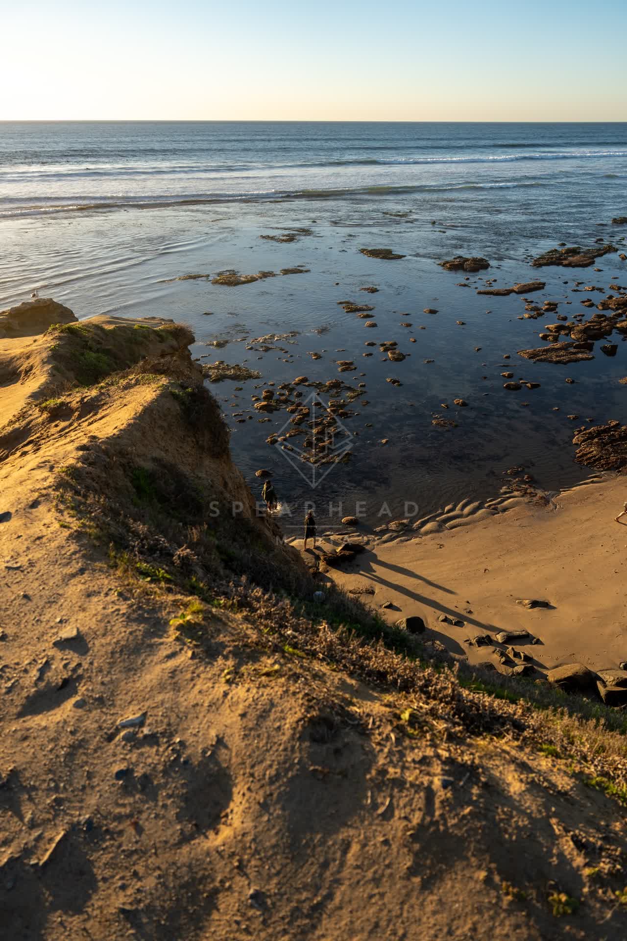 Elevated view of the cliffs, the surf and the ocean at Sunset Cliffs, with people walking.
