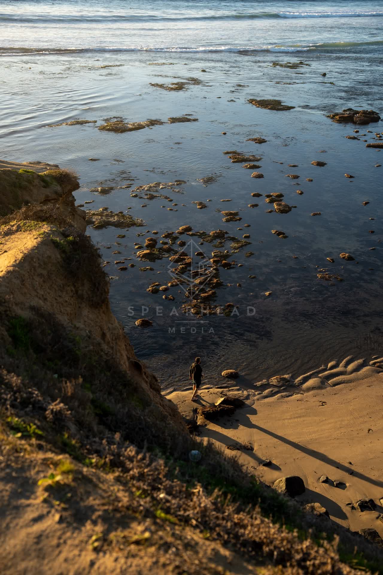 Elevated view of the cliffs, the ocean and the beach at Sunset Cliffs, with people walking.