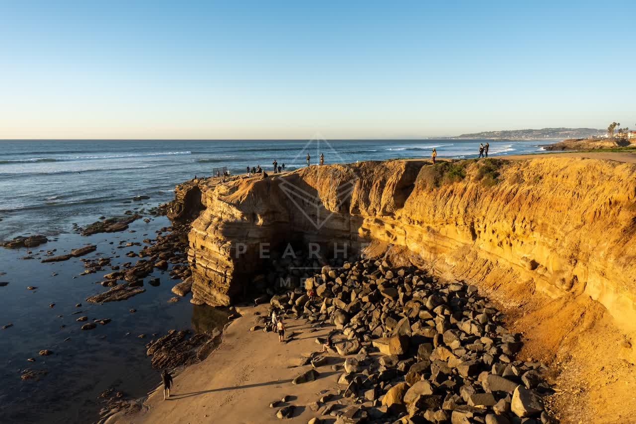 Elevated view of the cliffs, the surf and the ocean at Sunset Cliffs, with people walking.