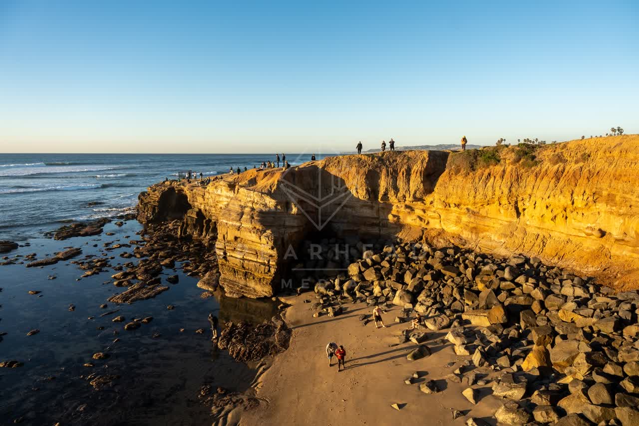 Elevated view of the cliffs, the surf and the ocean at Sunset Cliffs, with people walking.