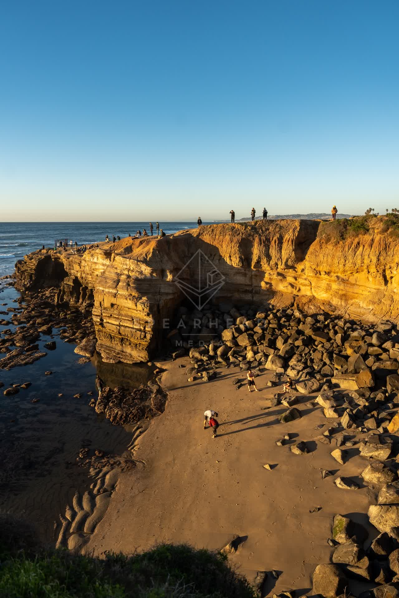 Elevated view of the cliffs, the surf and the ocean at Sunset Cliffs, with people walking.
