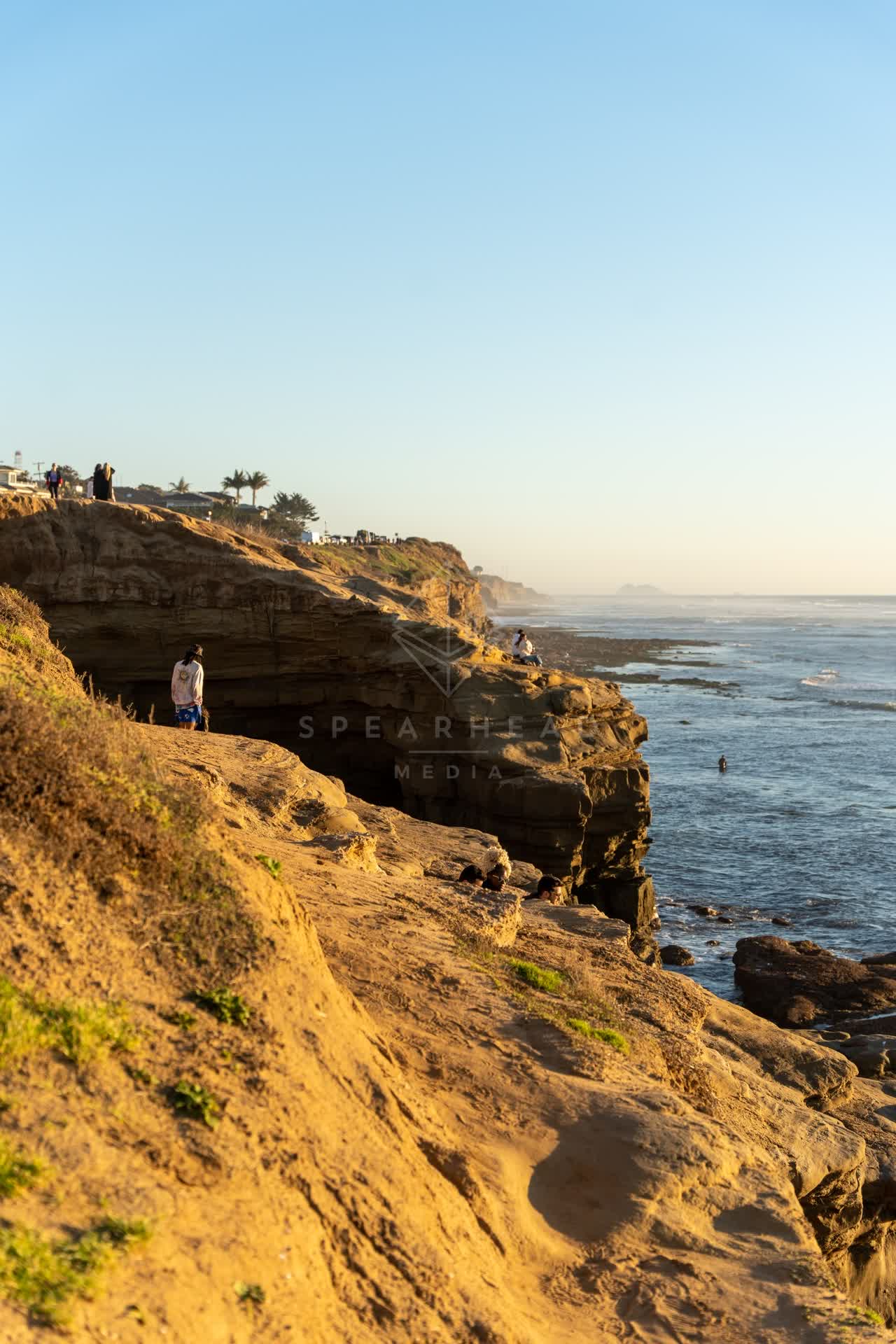 Elevated view of the cliffs, palm trees and the ocean at Sunset Cliffs, with people walking.