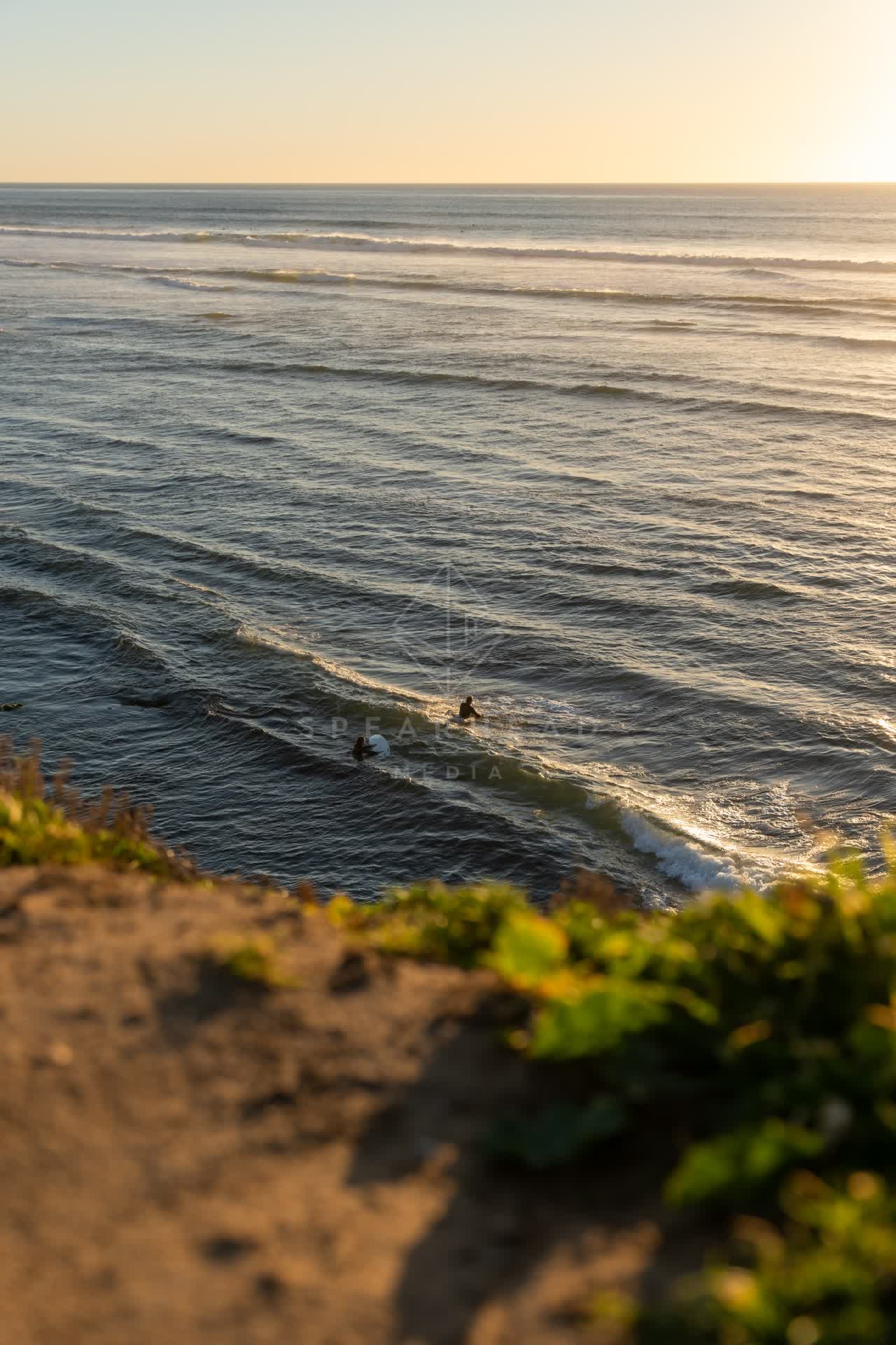 Elevated view of the cliffs, the surf and the ocean at Sunset Cliffs, with surfers out.