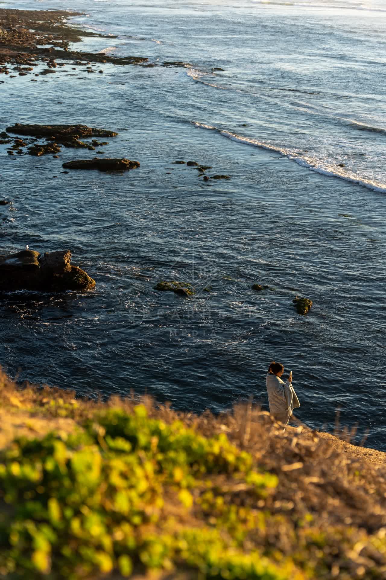 Elevated view of the cliffs, the surf and the ocean at Sunset Cliffs, with people walking.