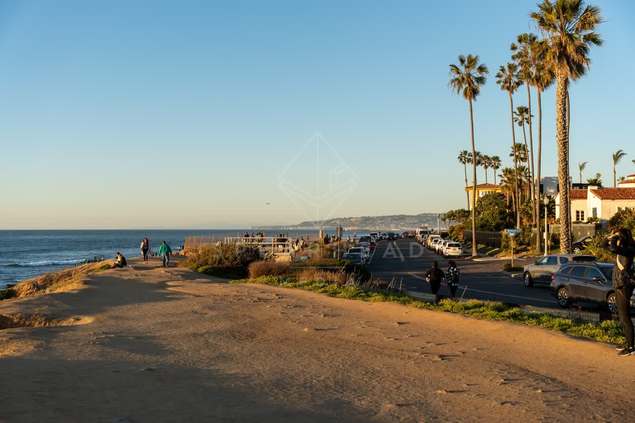 The cliffs, palm trees and the ocean at Sunset Cliffs, with people walking.
