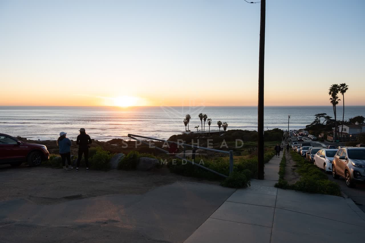 Elevated view of the cliffs, palm trees and the ocean at Sunset Cliffs, with people walking.