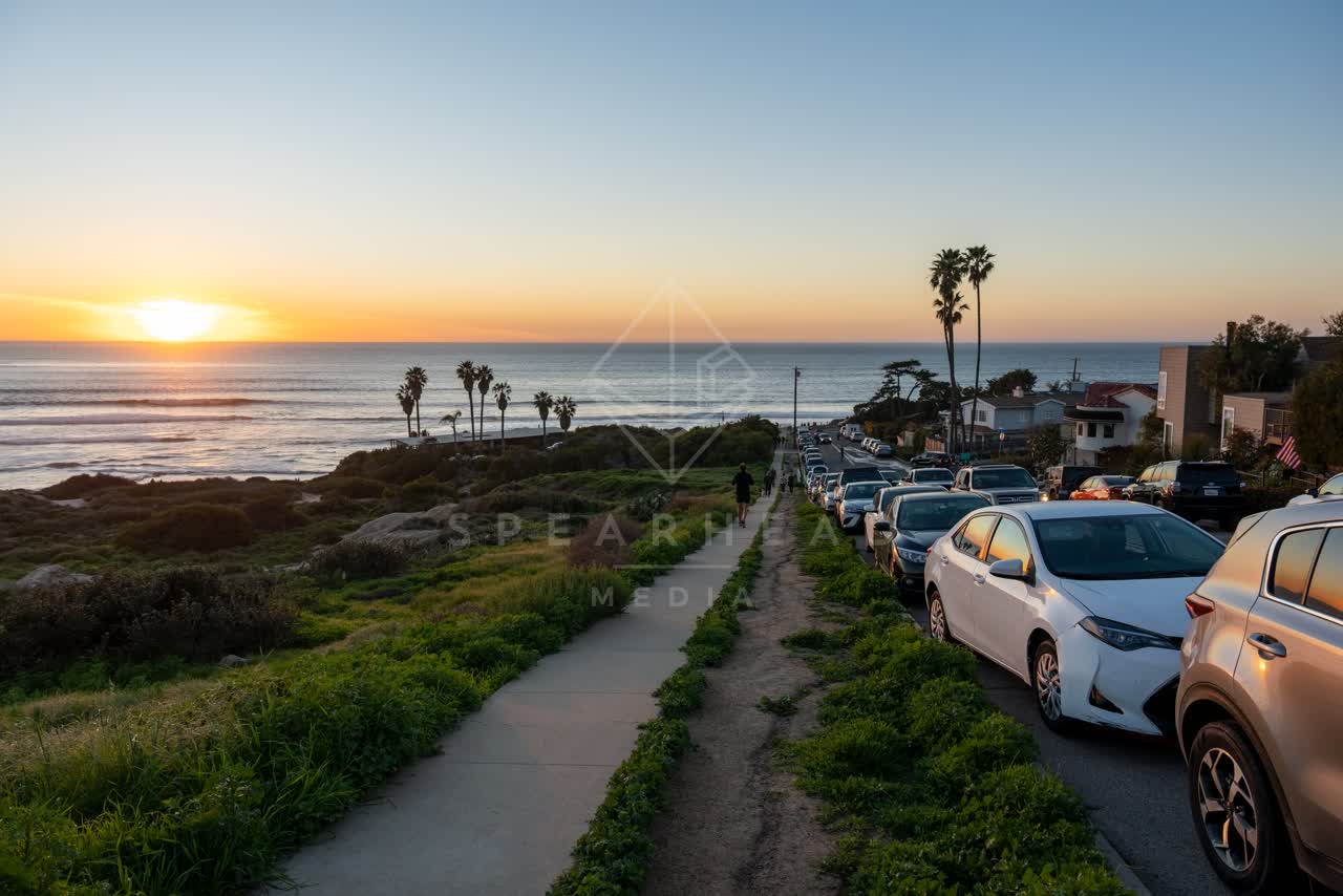 Elevated view of the cliffs, palm trees and the ocean at Sunset Cliffs, with people walking.