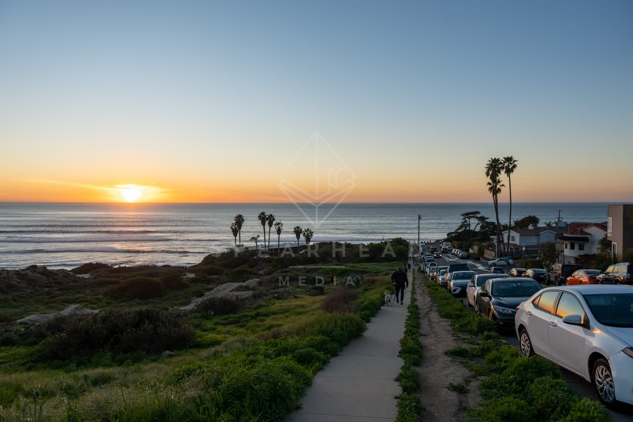 Elevated view of the cliffs, palm trees and the ocean at Sunset Cliffs, with people walking.