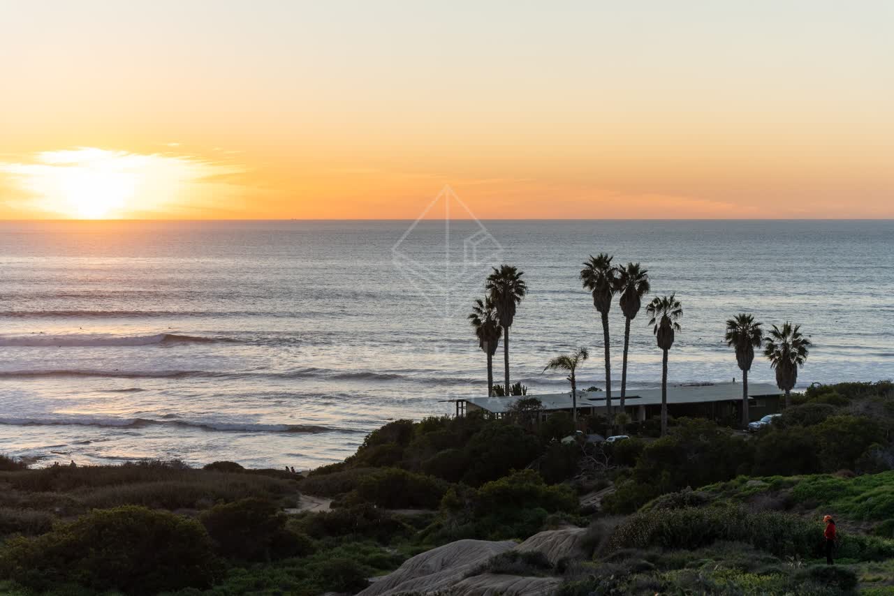 Elevated view of the cliffs, the surf and palm trees at Sunset Cliffs.