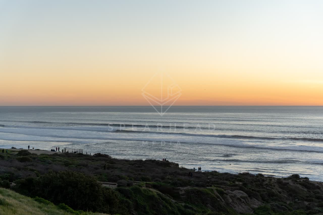 Elevated view of the cliffs, the surf and the ocean at Sunset Cliffs, with people walking.