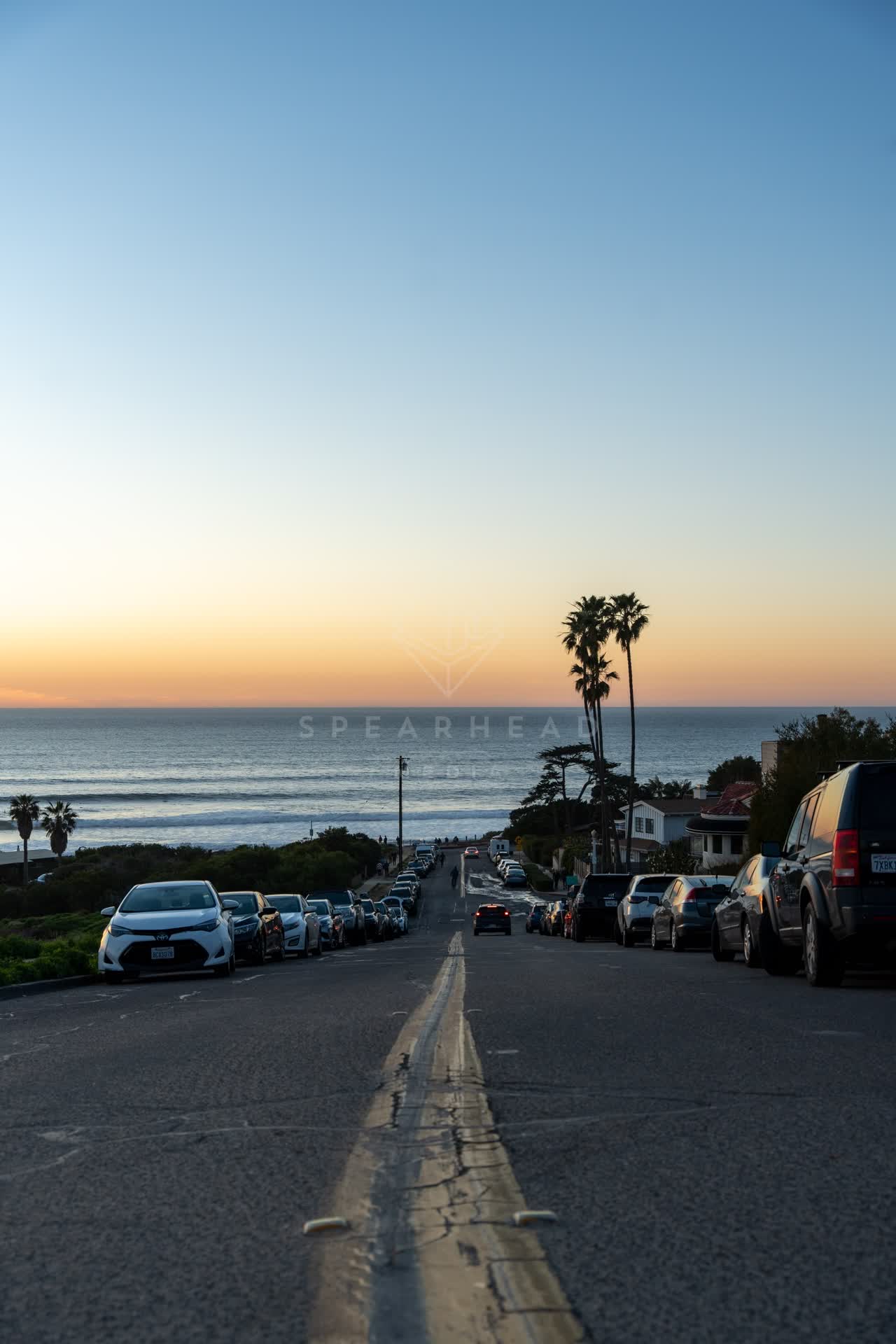 A residential street, palm trees and the ocean at Sunset Cliffs.