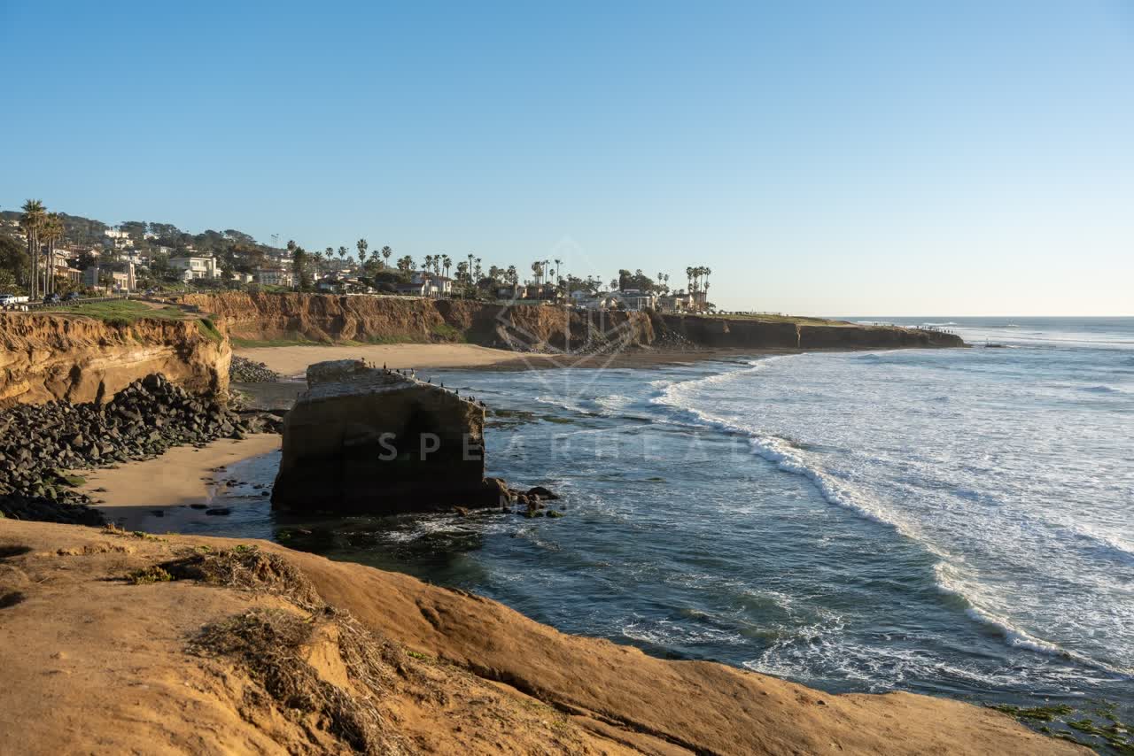 Elevated view of the cliffs, the surf and palm trees at Sunset Cliffs.