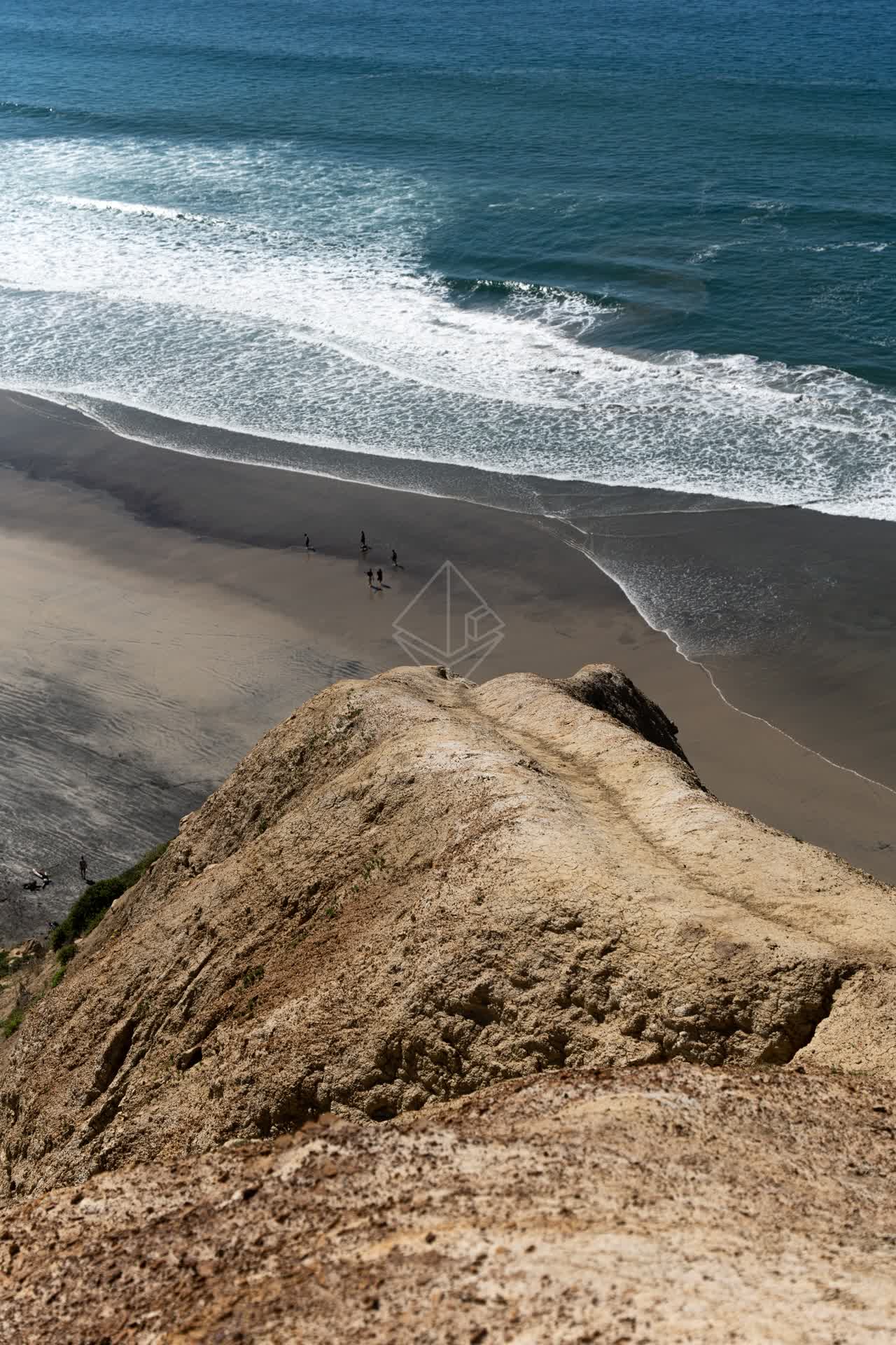 Elevated view of the cliffs, the surf and the ocean at Torrey Pines, with people walking.