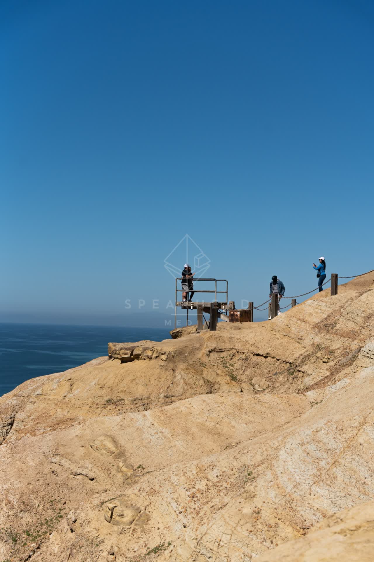 Elevated view of the cliffs, the ocean and open country at Torrey Pines, with people walking.
